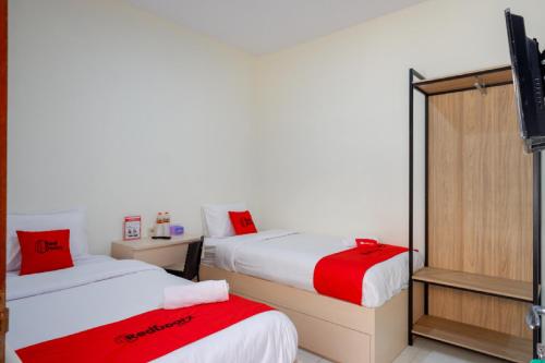 a room with two beds with red and white sheets at RedDoorz near Alun Alun Kudus 2 in Kudus