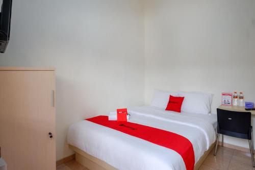a bedroom with a large white bed with red pillows at RedDoorz near Alun Alun Kudus 2 in Kudus