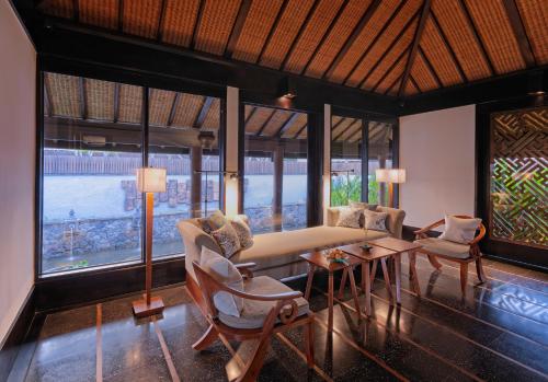 a living room with a couch and chairs and windows at The Legian Seminyak, Bali in Seminyak