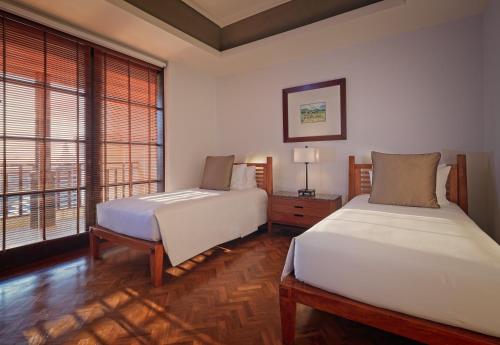 a bedroom with two beds and a large window at The Legian Seminyak, Bali in Seminyak