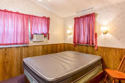 a bed in a room with pink curtains at Williamsburg Camping Resort Wheelchair Accessible Park Model 7 in Croaker