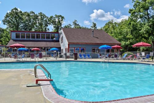 a pool with chairs and umbrellas at a resort at Williamsburg Camping Resort One Bedroom Loft Cabin 4 in Croaker