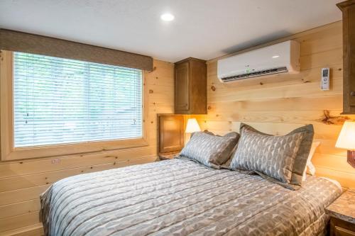 1 dormitorio con cama y ventana en Williamsburg Camping Resort 38 ft. Park Model 5, en Croaker