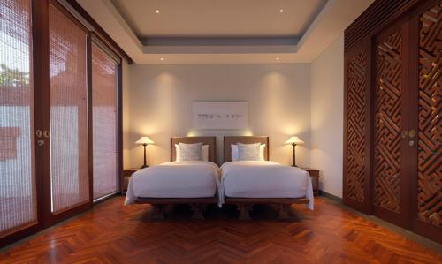 a bedroom with two beds and a large window at The Legian Seminyak, Bali in Seminyak