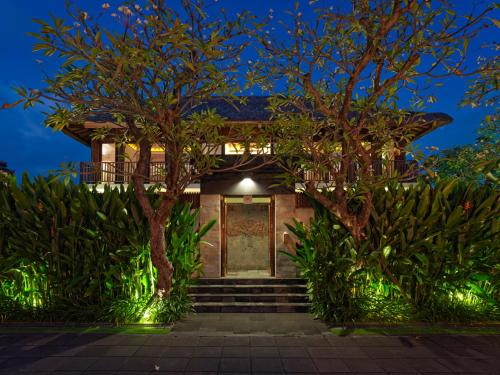 a house with a gate and trees at night at The Legian Seminyak, Bali in Seminyak