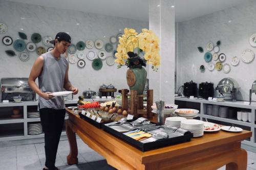 a man standing in a kitchen holding a plate at Lanna Oriental Hotel in Chiang Mai