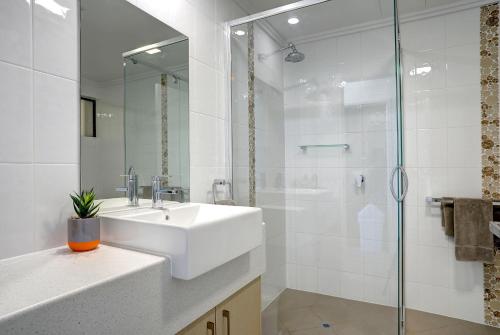 a white bathroom with a sink and a shower at Limani Motel in Port Lincoln