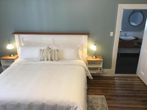una camera da letto con un grande letto bianco con due lampade di Harrison House a Strahan