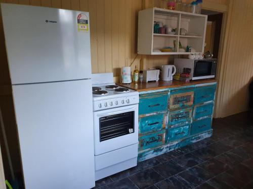 a kitchen with a white stove and a refrigerator at Golden Mt Rest off Pepperina Lane in Mount Morgan