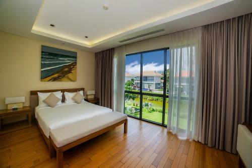a bedroom with a bed and a large window at The Ocean Villas Managed by The Ocean Resort in Da Nang