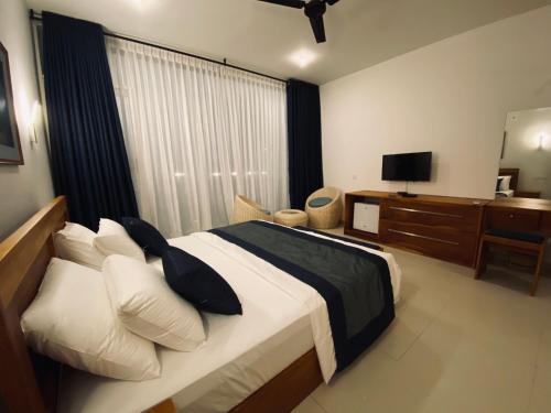 a bedroom with a large bed and a television at The Lighthouse Negombo in Negombo