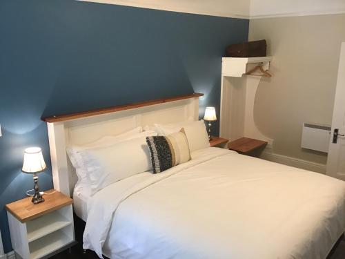 a bedroom with a white bed with a blue wall at Harrison House in Strahan