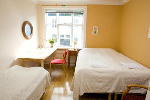 Habitación con 2 camas, mesa y ventana en Butterfly Guesthouse, en Reikiavik
