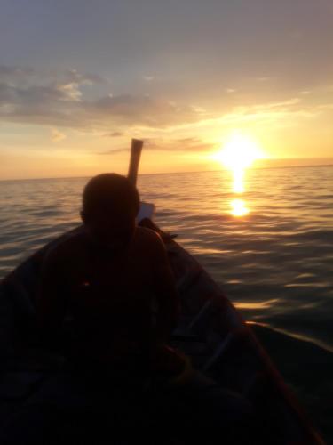 a person in a boat in the ocean at sunset at Andaman Bay House in Ko Lanta