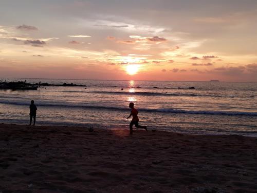 Andaman Bay House في كو لانتا: شخصان يركضان على الشاطئ عند غروب الشمس