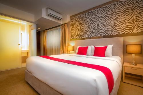 a bedroom with a large white bed with red pillows at Royce Hotel @ KL Sentral in Kuala Lumpur