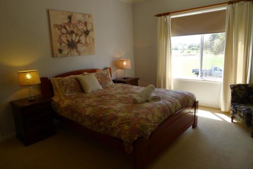 a bedroom with a large bed with a window at BEACHPOINT COTTAGE in Warrnambool
