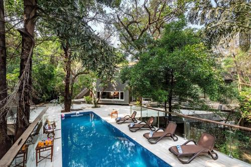 KhandālaにあるSaffronStays Odeon, 4 BDR Heritage Bungalow In The Heart Of Khandalaの長椅子と家のあるプール