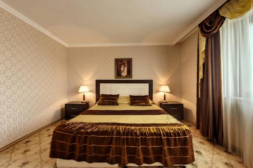 a bedroom with a large bed and two lamps at Merian Palace Hotel in Stara Zagora