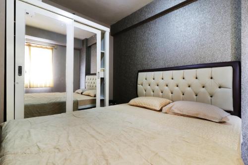 a bedroom with a large bed and a mirror at Apartment Kalibata City by Novi in Jakarta