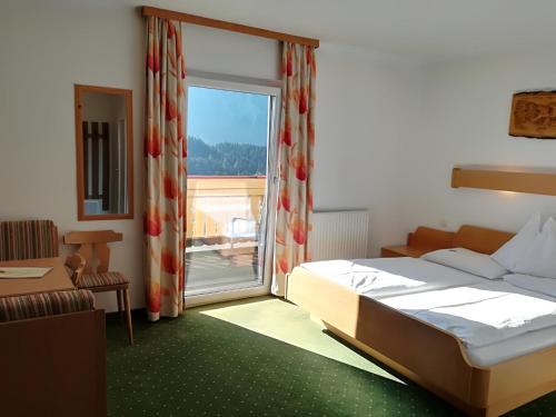 a bedroom with a bed and a large window at Hotel Pension Sonnenuhr in Tauplitz