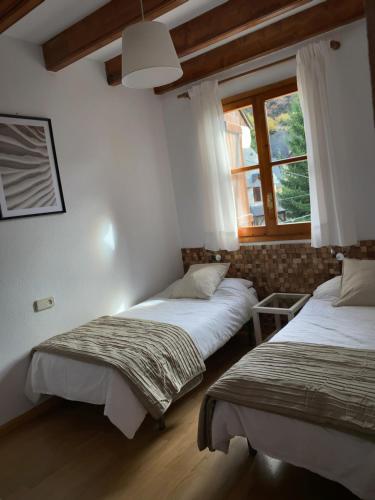 2 camas en una habitación con ventana en Chalet Los Ibones - Lodge Escarrilla, en Escarrilla