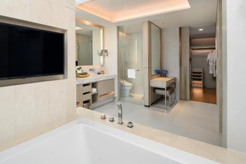 a bathroom with a tub and a tv and a sink at Hotel Nikko Bangkok in Bangkok