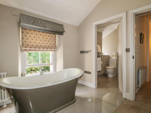 ein großes Badezimmer mit Badewanne und Fenster in der Unterkunft Stair Cottage in Keswick