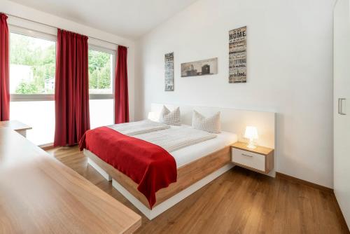 a bedroom with a bed with a red blanket on it at Pension Gschaider in Payerbach