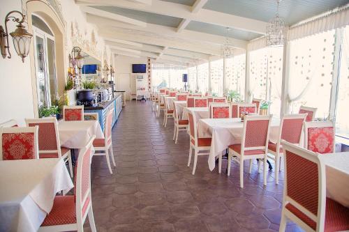 une salle à manger avec des tables et des chaises blanches dans l'établissement Hotel Staroyamskaya, à Torzhok