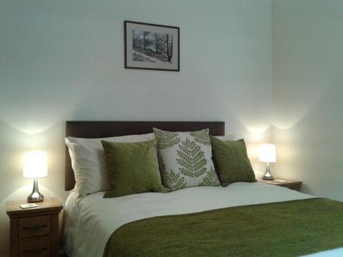 a bedroom with a bed with green pillows and two lamps at Millcroft in Penrith