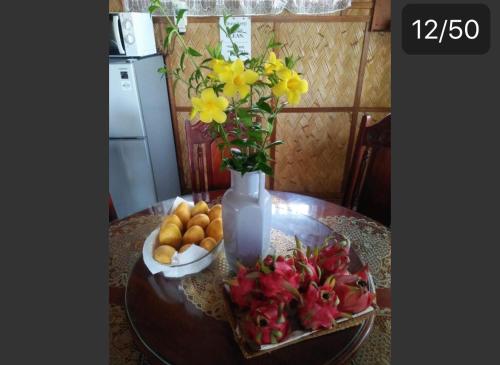 a table with a vase with flowers and fruit on it at Seabreeze Beachfront Home and Cottages new management in San Juan