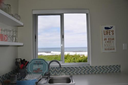 a kitchen sink with a window with a view of the ocean at Beach Villa Apartment in Hermanus