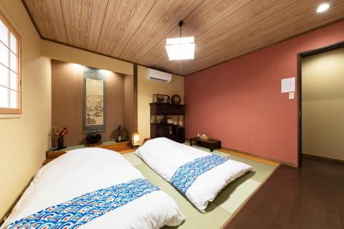 two beds in a room with a red wall at Shirakabanoyado - Nakamichi in Osaka