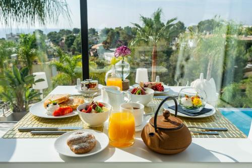 einen Frühstückstisch mit Frühstückszutaten und Orangensaft in der Unterkunft Portals Hills Boutique Hotel in Portals Nous