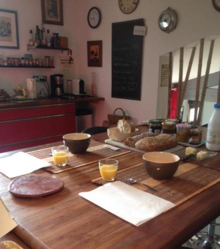 - une table en bois avec des bols et des verres de jus d'orange dans l'établissement Cévennes / Méditerranée, à Quissac