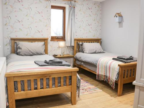 a bedroom with two beds and a window at Woodman's Lodge in Nantwich