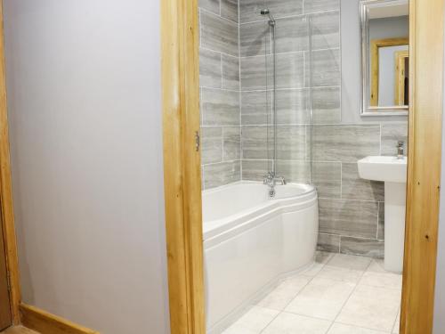 a bathroom with a white tub and a sink at Woodman's Lodge in Nantwich