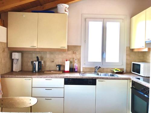 a kitchen with white cabinets and a sink at Comano Lugano Ticino - B&B Walterina in Comano
