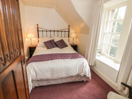 a bedroom with a large bed and two windows at Near Bank Cottage in Eyemouth