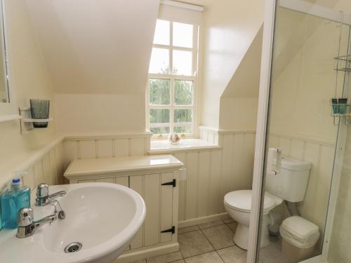 a white bathroom with a sink and a toilet at Near Bank Cottage in Eyemouth