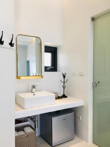 a bathroom with a white sink and a mirror at Sea Shore Hotel in Manzhou