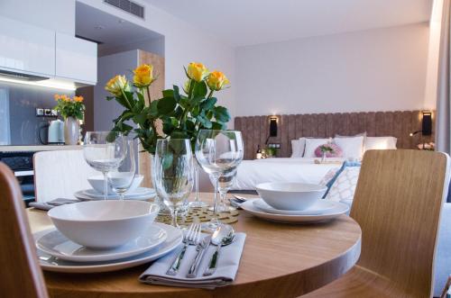 a table with plates and glasses and flowers on it at Verde Apartments CENTRUM klimatyzacja in Koszalin