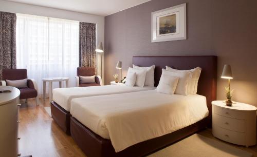 ein Hotelzimmer mit einem großen Bett mit weißer Bettwäsche in der Unterkunft Altis Suites Apartamentos Turísticos in Lissabon