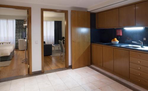 a kitchen with wooden cabinets and a living room at Altis Suites Apartamentos Turísticos in Lisbon