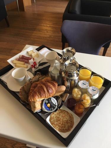 a tray of breakfast foods on a table at Hotel Le Temps De Vivre in Roscoff