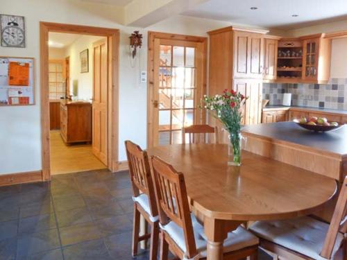 a kitchen with a wooden table with a vase of flowers on it at An Torr in Newtonmore