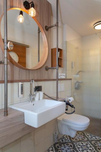 a bathroom with a sink and a toilet and a mirror at Hotel Luise & Luisenhof in Dinkelsbühl