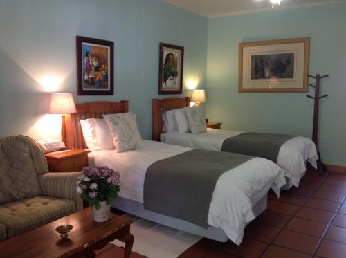 um quarto de hotel com duas camas e um sofá em Chez Esme Guest House em Roodepoort