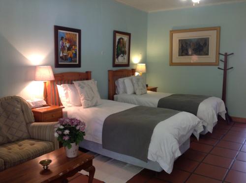 a hotel room with two beds and a couch at Chez Esme Guest House in Roodepoort
